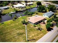 Waterfront home with boat dock on canal, surrounded by lush greenery and neighboring homes at 27193 And 27197 Voyageur Dr, Punta Gorda, FL 33983