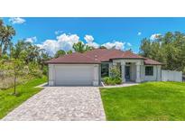 Beautiful single-story home featuring a brick driveway, lush lawn, and attached two car garage at 2955 Carmela Ave, North Port, FL 34286