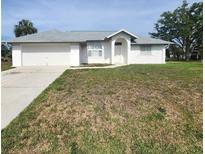 Charming single-story home featuring a clean white exterior, attached garage and a well-maintained lawn at 4390 Wischamper St, Port Charlotte, FL 33948