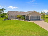 Charming single-story home featuring a manicured lawn, screened garage, and inviting front entrance at 69 Bunker Rd, Rotonda West, FL 33947