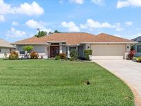 Beautiful single-story home featuring a well-manicured lawn, a two-car garage, and a lovely front yard with mature landscaping at 85 Long Meadow Ct, Rotonda West, FL 33947