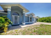 Charming single-story home with blue exterior, decorative front door, and well-maintained landscaping at 12185 Weimar Ave, Port Charlotte, FL 33981