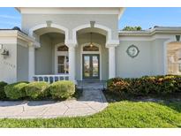 Elegant home entrance with decorative pillars, stone walkway, and manicured landscaping at 13783 Palmetto Point Ct, Port Charlotte, FL 33953