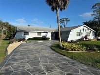 Charming single-story home with lush landscaping and an inviting stone-pattern driveway at 1505 Kenmore St, Port Charlotte, FL 33952