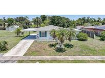 Charming single story home with attached carport, well-manicured lawn, and mature landscaping at 1596 Hayworth Rd, Port Charlotte, FL 33952