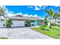 Charming single-story home featuring stone accents, a paved driveway, and lush landscaping with palm trees at 192 Danforth S Dr, Port Charlotte, FL 33980