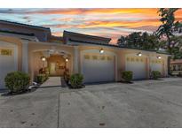 Inviting condo exterior with two-car garage, manicured bushes, and colorful sunset sky backdrop at 206 Gondola Park Dr # 206, Venice, FL 34292