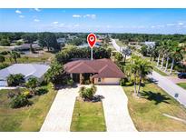 Spacious single-Gathering home with a large front yard, palm trees and a long driveway on a sunny day at 25538 Rampart Blvd, Punta Gorda, FL 33983