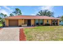 Charming single-story home with brick driveway, well-maintained lawn, and mature trees on a sunny day at 2626 Auburn Blvd, Port Charlotte, FL 33948