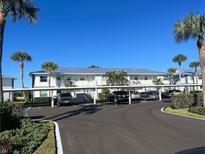 Exterior of the condo with covered parking, blue skies, and palm trees at 26430 Rampart Blvd # 511, Punta Gorda, FL 33983
