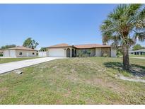 Charming single-story home featuring an attached garage, concrete drive and mature palm trees at 1039 Marlene St, Port Charlotte, FL 33952