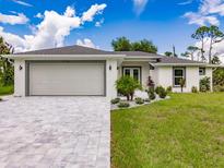 Beautiful single-story home featuring a well-manicured lawn, brick driveway, and two-car garage at 17130 Elder St, Port Charlotte, FL 33954