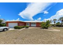 Charming coral home with a white metal roof, lush landscaping, and a welcoming front entrance at 190 Casa Ln, Punta Gorda, FL 33950