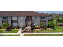 A tan condo with brown accents shows stairs to the second floor entrance, and beautifully landscaped grounds at 25100 Sandhill Blvd # I-204, Punta Gorda, FL 33983