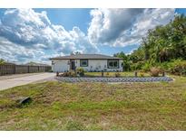 Charming single-story home with a well-manicured lawn, attractive landscaping, and a driveway leading to an attached garage at 4044 S Salford Blvd, North Port, FL 34287