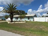 Charming single-story home featuring a landscaped front yard with a majestic palm tree and white picket fence at 4089 Yucatan Cir, Port Charlotte, FL 33948