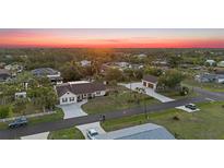 Beautiful aerial view of home with spacious yard, detached garage, and lovely sunset at 4317 Mccullough St, Port Charlotte, FL 33948