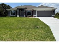 Charming single story home featuring a two car garage, manicured lawn, and a covered entryway at 13346 High Springs Ave, Port Charlotte, FL 33981