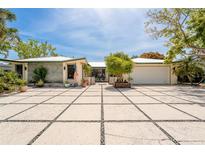Charming single-story home featuring an expansive paved driveway and lush tropical landscaping at 155 Donna Ct, Punta Gorda, FL 33950