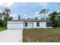 Charming single-story home with a modern white exterior and a well-manicured front lawn at 16218 Chamberlain Blvd, Port Charlotte, FL 33954