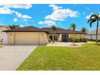 Inviting single-story home featuring a manicured lawn, palm trees, and a neutral-toned exterior paint at 2152 Taiwan Ct, Punta Gorda, FL 33983