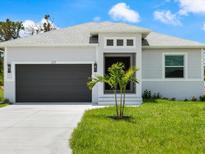 Charming single Gathering home featuring a grey exterior, two-car garage, and a well manicured lawn at 223 Australian Dr, Rotonda West, FL 33947