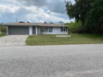 Charming single-story home featuring a well-maintained lawn and a gray two-car garage at 23220 Rountree Ave, Port Charlotte, FL 33980