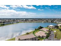 Expansive aerial view of a home by a lake in a gated community with lush landscaping at 26333 Nadir Rd # 111, Punta Gorda, FL 33983