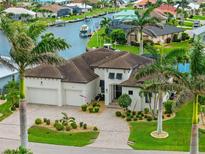 Beautiful waterfront home with a brick driveway, two-car garage, tile roof, and tropical landscaping at 3353 Sandpiper Dr, Punta Gorda, FL 33950