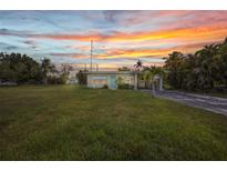 Charming single-story home featuring a large grassy lawn with tropical trees at a colorful sunset at 426 Burland St, Punta Gorda, FL 33950