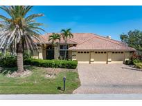 Charming single-story home with a brick driveway, three-car garage, and lush landscaping at 5023 Key Largo Dr, Punta Gorda, FL 33950