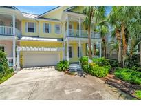 Charming yellow home with a two-car garage, white trim, double porches, and tropical landscaping at 936 Hemingway Cir, Tampa, FL 33602