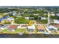 Waterfront home featuring a private dock, screened pool, and lush tropical landscaping at 9582 Arsipe Cir, Port Charlotte, FL 33981