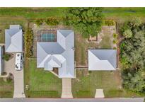 This aerial view showcases a home with a metal roof, an in-ground pool, an oversized lot, and an RV parking area at 1761 Okolona St, North Port, FL 34287