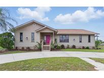 Charming single-story home with a manicured front yard and pink front door at 22349 Columbus Ave, Port Charlotte, FL 33954