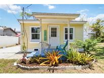 Charming yellow home featuring a cozy front porch with a welcome sign and a small, landscaped garden at 233 N New York Ave, Englewood, FL 34223