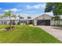 Charming single-story home featuring a well-manicured lawn, brick driveway, and a two-car garage at 425 Corrientes Cir, Punta Gorda, FL 33983