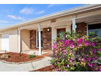 Charming brick home featuring a covered entrance, columns, and vibrant pink azalea bushes at 125 Small Se St, Port Charlotte, FL 33952