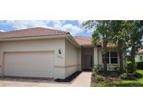 Charming single-story home with a tile roof, manicured landscaping, and an attached two-car garage at 13256 Creekside Ln, Port Charlotte, FL 33953