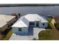 Waterfront property with a freshly painted exterior, metal roof, and well-maintained landscaping at 3772 Peace River Dr, Punta Gorda, FL 33983