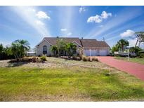 Charming single-story home with a three-car garage, well-maintained landscaping, and a red brick driveway at 5219 Guava Ter, Port Charlotte, FL 33981