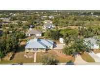 Beautiful home featuring a metal roof, screened-in porch, lush landscaping, and a private driveway at 13204 Kakapo Ave, Port Charlotte, FL 33981