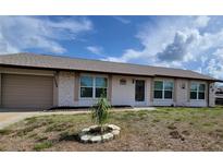 Charming home featuring stone accents, a well-kept lawn, and an attached garage, perfect for comfortable living at 13366 Ballon Ave, Port Charlotte, FL 33981