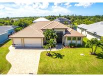 Beautiful home featuring a tile roof, an attached two-car garage, manicured landscaping, and a paved driveway at 13830 Begonia Cir, Port Charlotte, FL 33981
