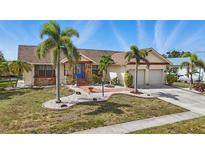 Charming home with a well-manicured lawn, lush landscaping, and a welcoming blue front door at 219 Tait Se Ter, Port Charlotte, FL 33952