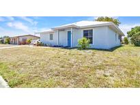 Charming light blue single-story home with a well-maintained lawn and a bright blue front door at 22299 Laramore Ave, Port Charlotte, FL 33952