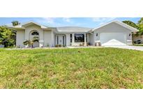 Well-maintained home featuring a clean white exterior, well manicured lawn, and an attached two car garage at 229 Waterside St, Port Charlotte, FL 33954
