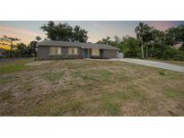 Charming single-story home featuring an attached garage, well-maintained front yard, and a welcoming blue front door at 23165 Glen Ave, Punta Gorda, FL 33980