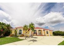 A beautiful yellow single Gathering home with a red tiled roof, arched windows, and a well maintained front yard at 3506 Saint Florent Ct, Punta Gorda, FL 33950