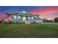 Charming two-story home with a well-manicured lawn and classic architectural details at sunset at 3548 Mondovi Ct, Punta Gorda, FL 33950